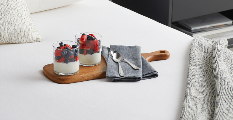 Two parfaits sitting on a dish on a bed